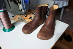 Handmade leather boots beside a sewing machine